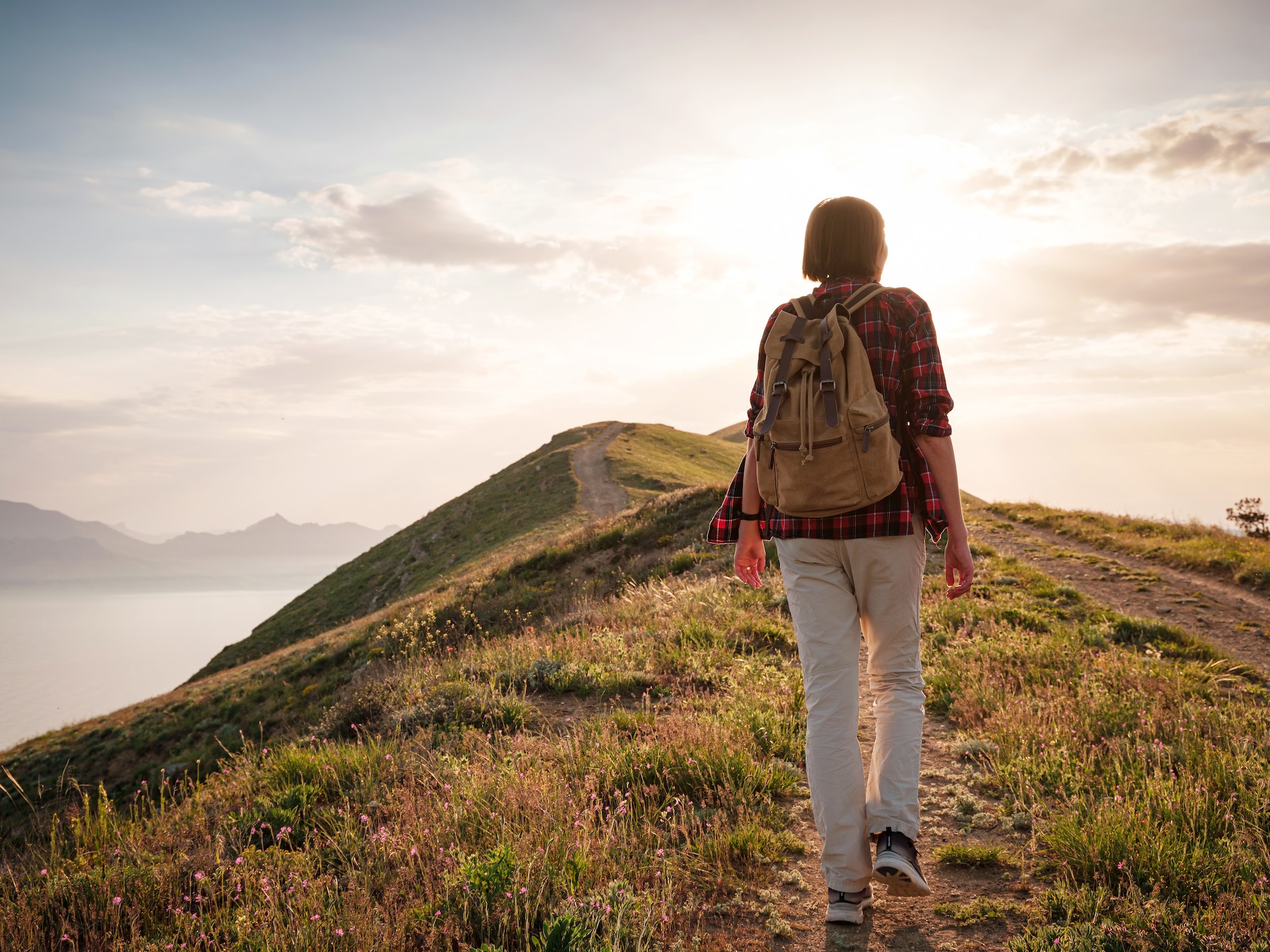 A young Asian woman with a backpack hiking in the summer.