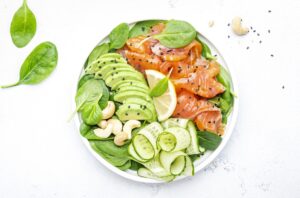 Salmon salad for ketogenic diet with avocado, spinach, cucumber, cashew nuts